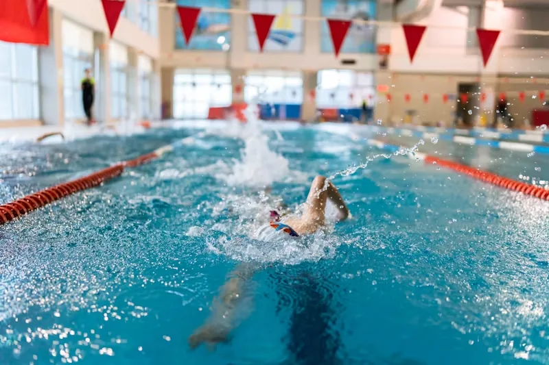 Person swims to strengthen the back muscles and ease the symptoms of a herniated disc.