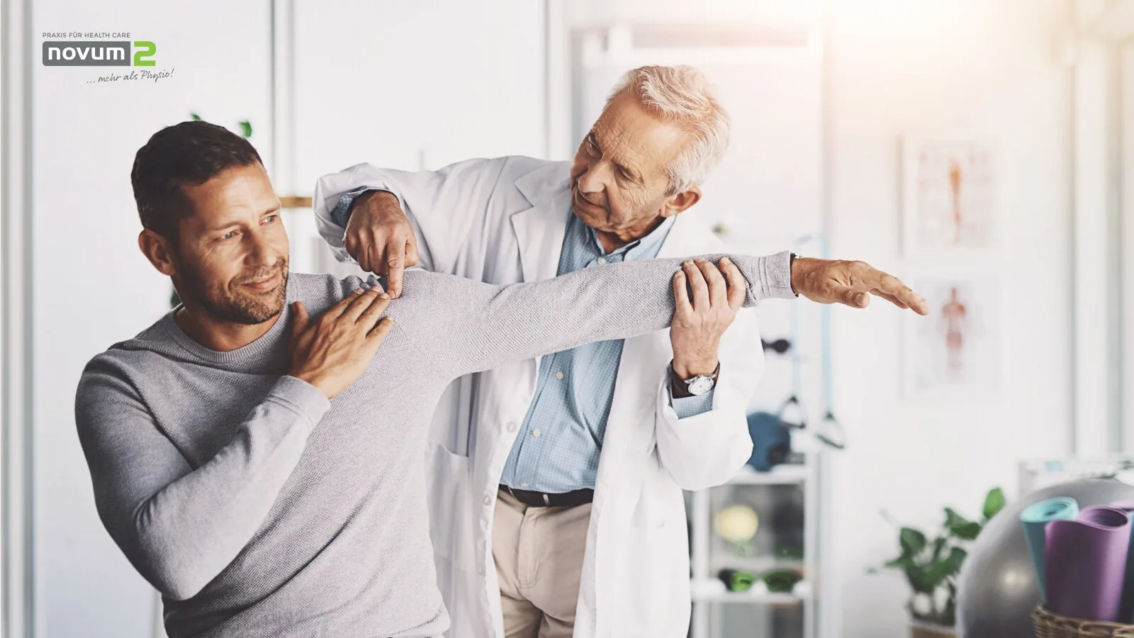 Arzt bei der Untersuchung und Therapie der Schulterbeweglichkeit eines Patienten bei Novum2.