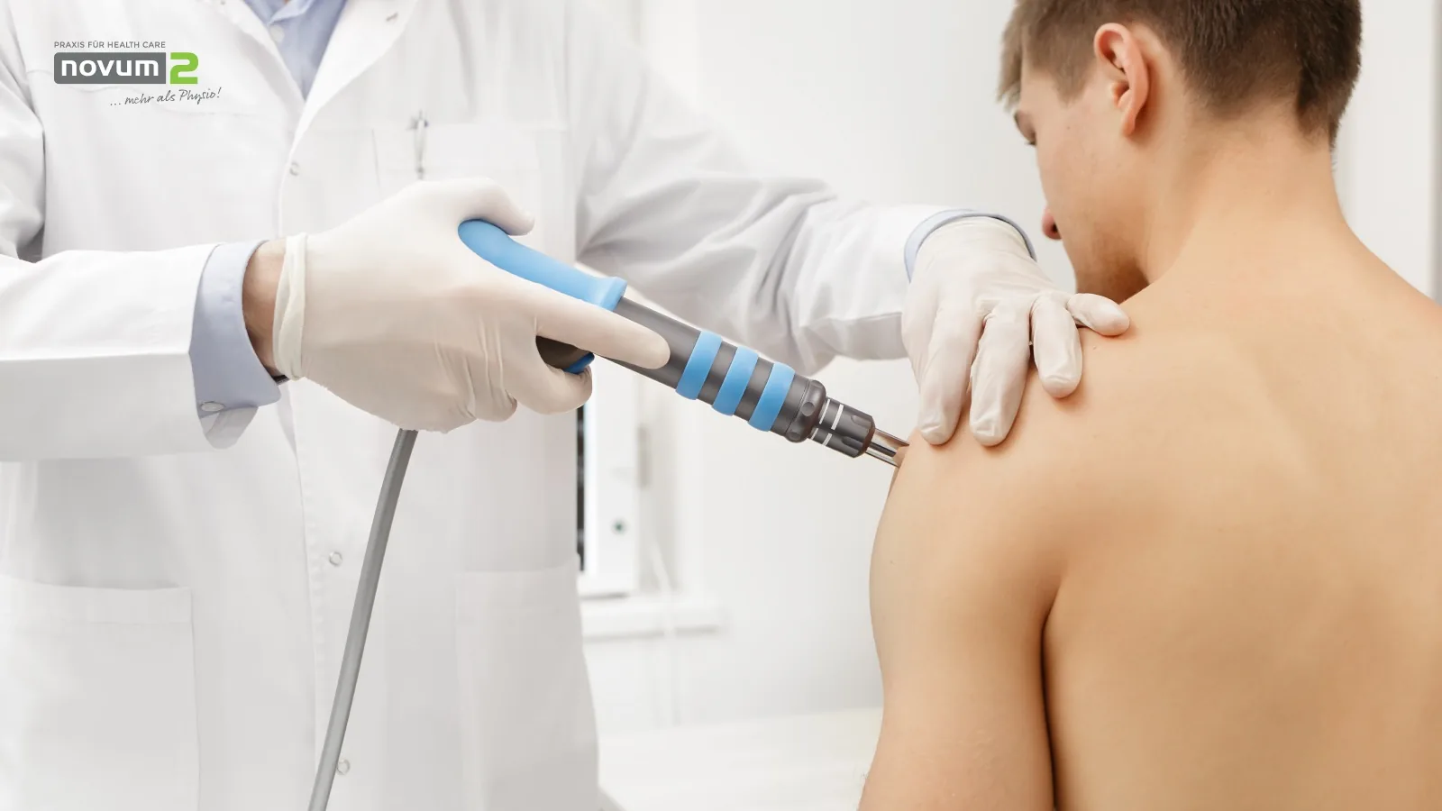 Arzt führt Stoßwellentherapie an der Schulter eines Patienten in der Novum2-Praxis durch